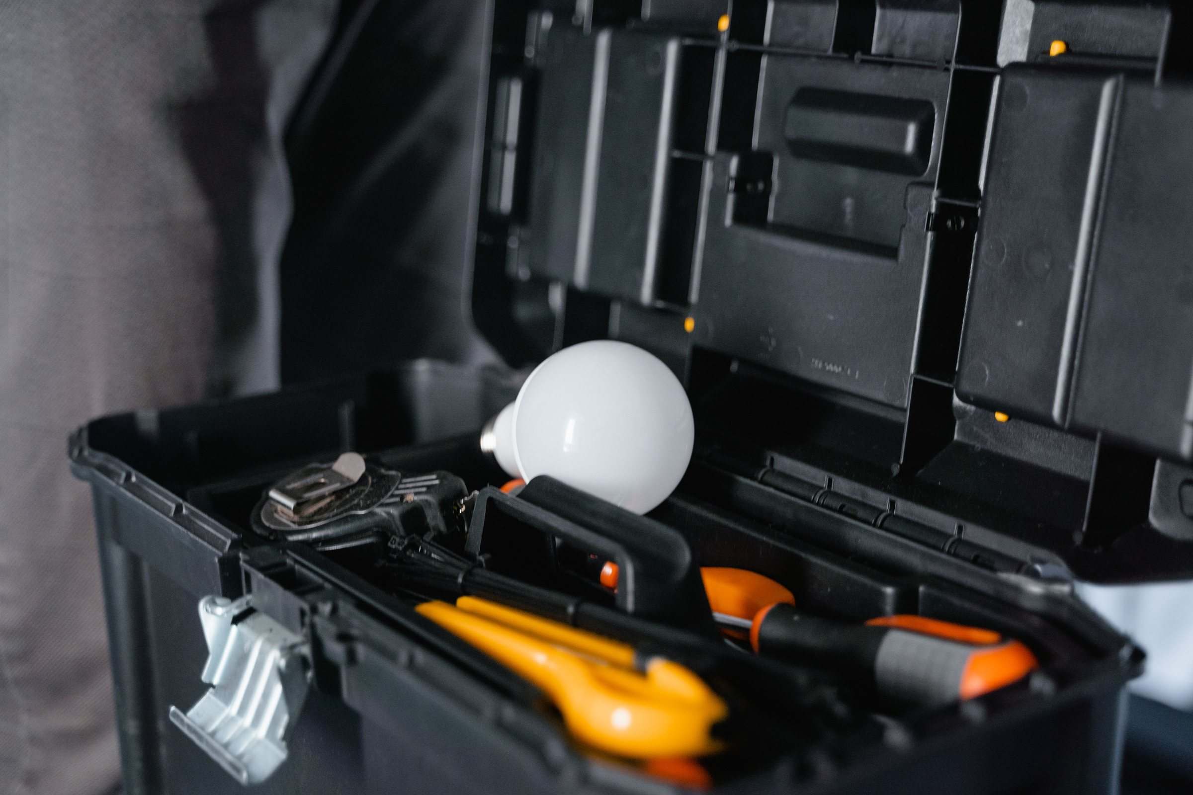An open toolbox with hand tools and a light bulb